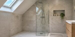 Upstairs wet room with a sloping ceiling, tiled shower floor, floor drain and clear glass screen